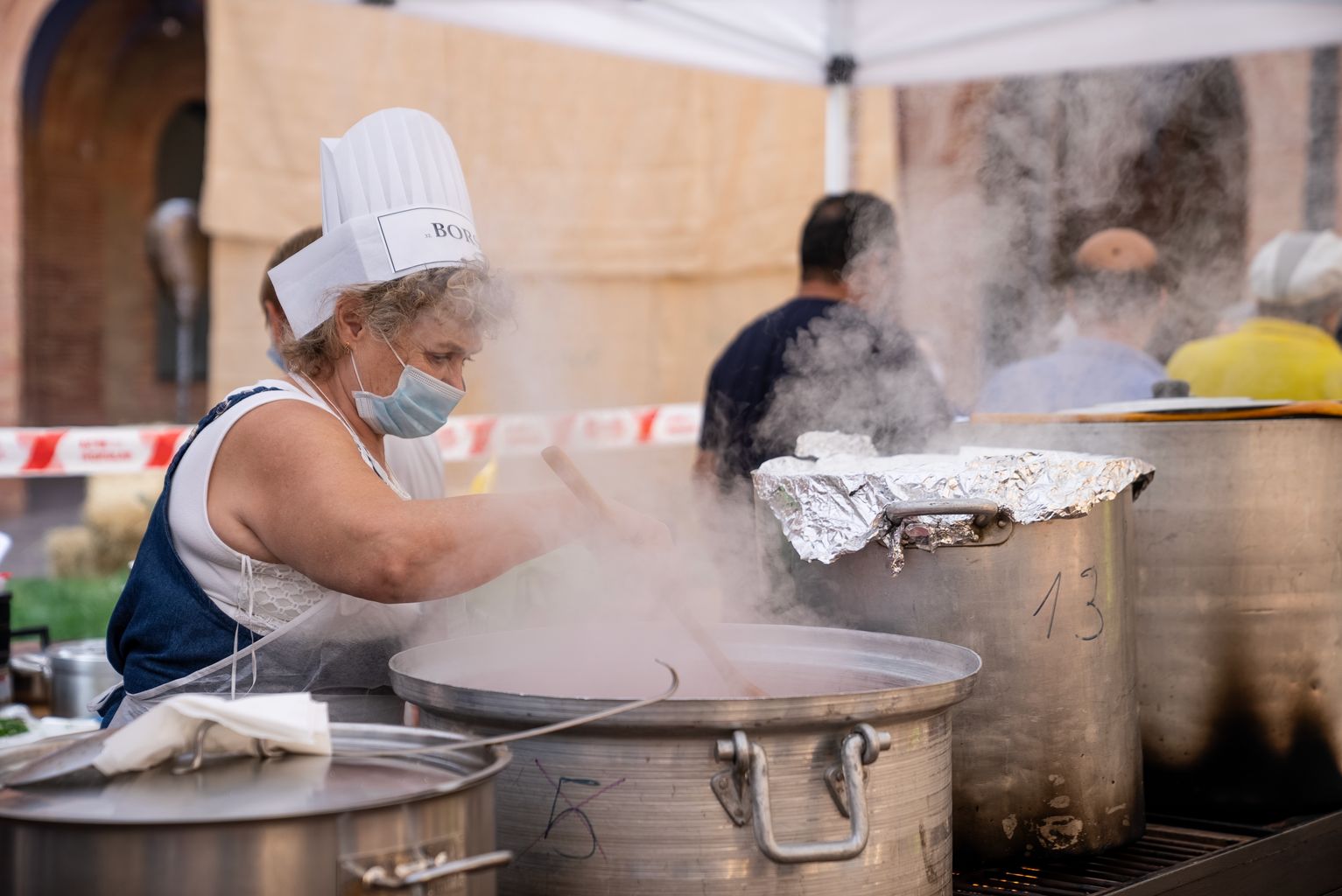 Una cuinera remena una de les olles en les quals s'està cuinant un dels plats presentats al Festival Sopes del Món
