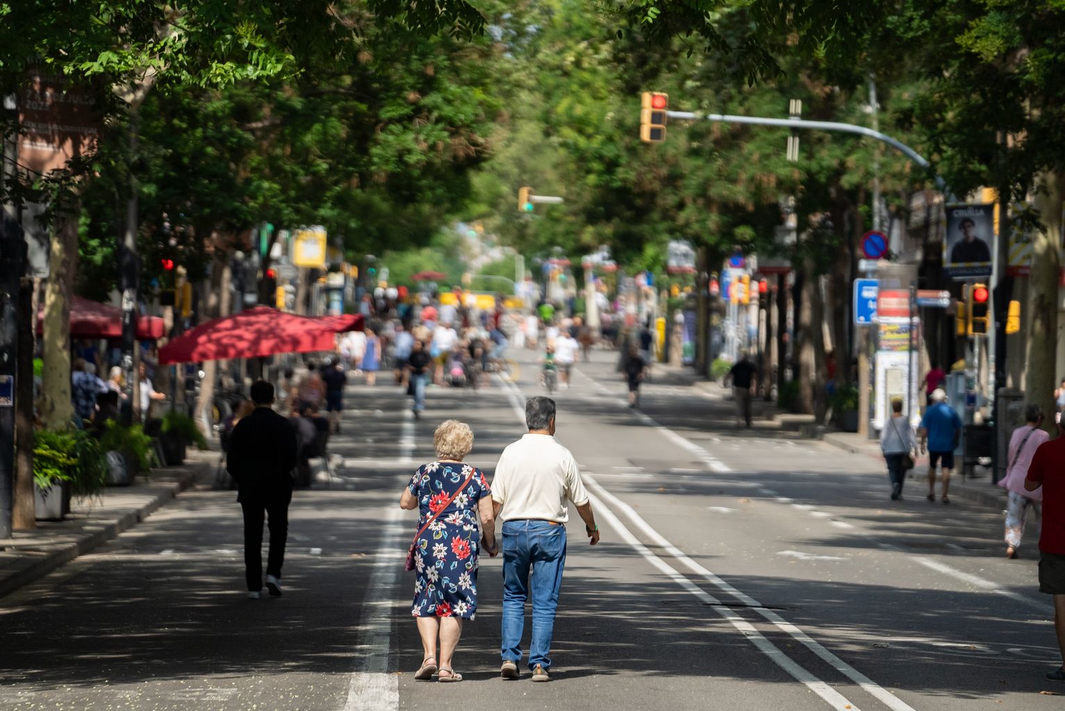 Un home i una dona caminant per la zona no apta per a vianants del carrer de Sants durant la jornada "Obrim Carrers" del 24 de juny.