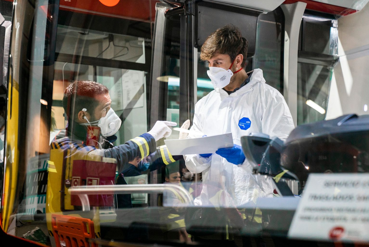 Un bomber parla amb un dels voluntaris de TMB que ja és dalt de l’autobús solidari