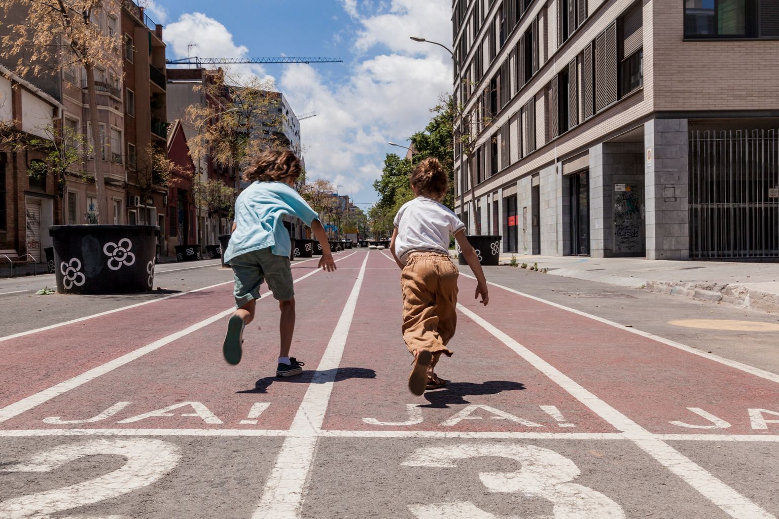 Dos nens corren per la pista de curses del carrer dels Almogàvers a la superilla del Poblenou