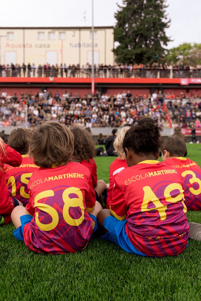 Infants, membres d’equips del Club Esportiu Martinenc, asseguts durant l’acte d’inauguració de la nova gespa i presentació dels equips del club
