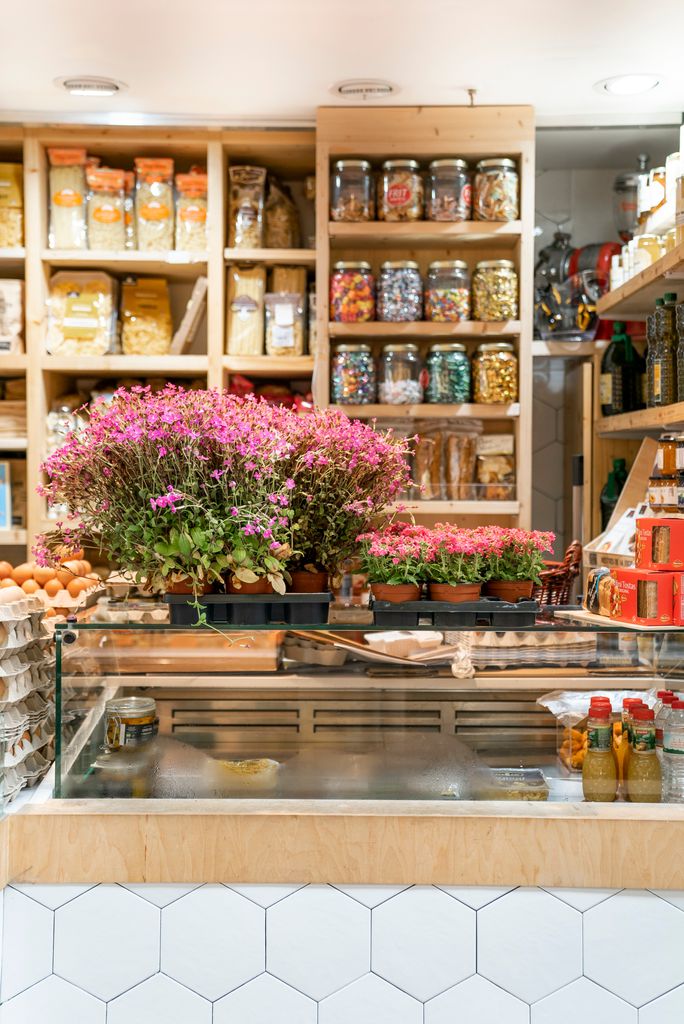 Mostrador d'una de les parades del Mercat de Sant Antoni amb torretes de flors de la campanya "Planta'm al balcó"