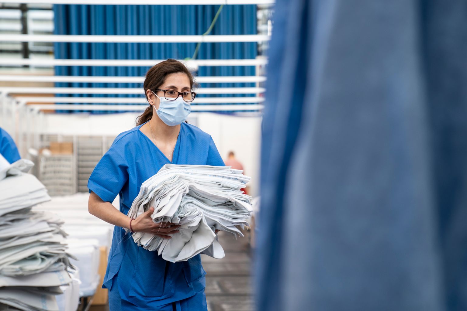Pavelló Salut Guinardó. Una membre del personal sanitari transporta la roba blanca per fer els llits