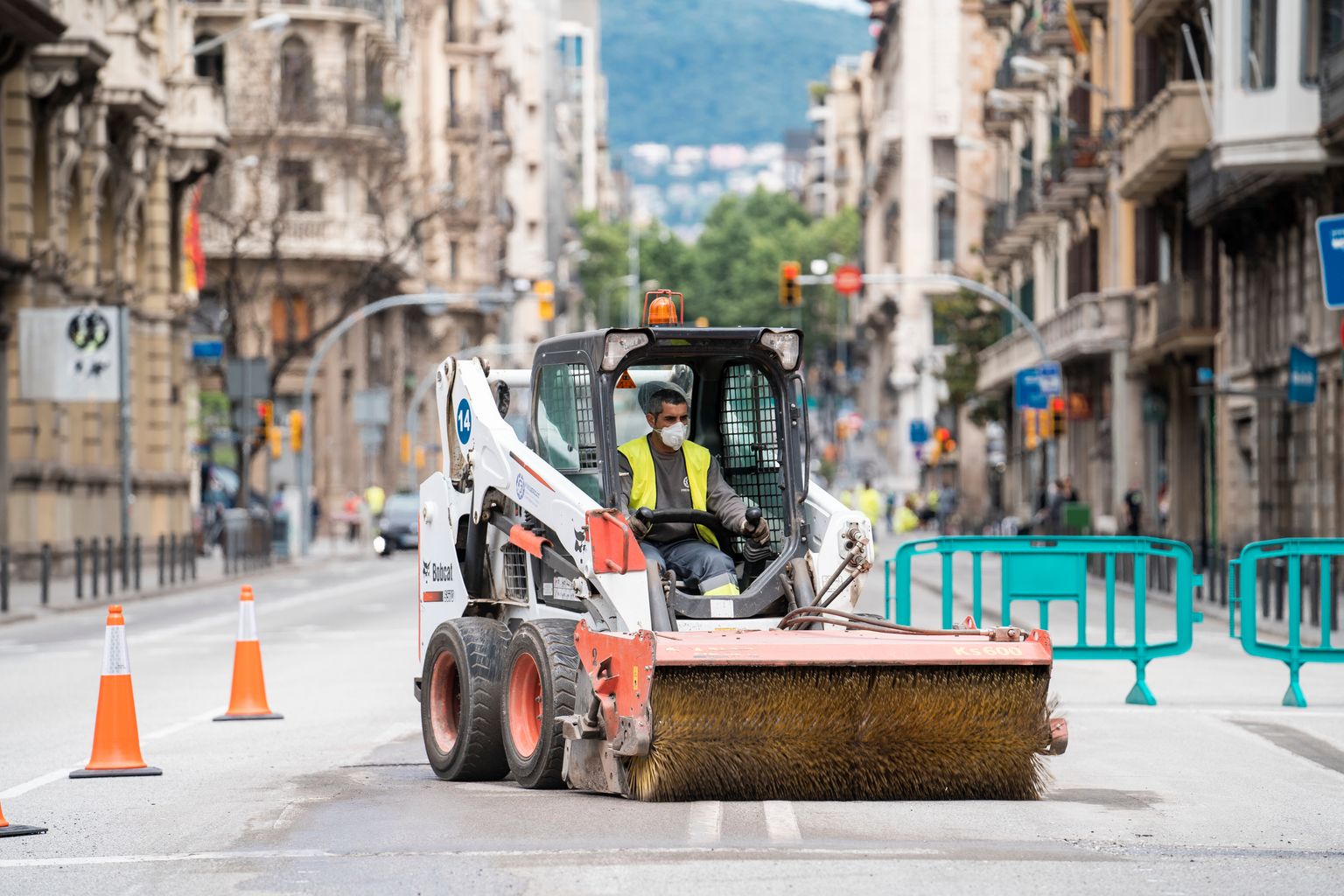 Un operari amb una Bobcat treballa sobre l'asfalt de la via Laietana durant les obres d'ampliació de les voreres