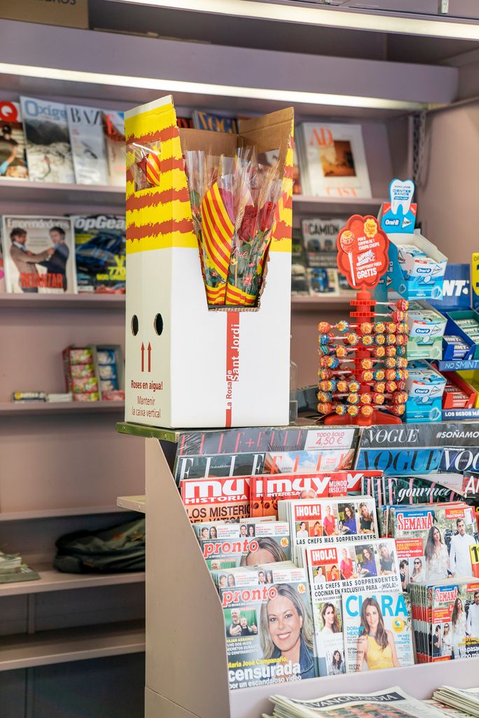 Caixa de roses de les distribuïdes per l’Ajuntament als quioscos de Diverscoop amb motiu de Sant Jordi. Al seu voltant, revistes i dolços