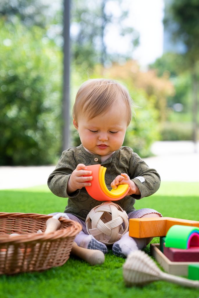 Un nadó juga amb unes peces de fusta a l'espai de joc 0-99 a la zona de la gran clariana de Glòries.