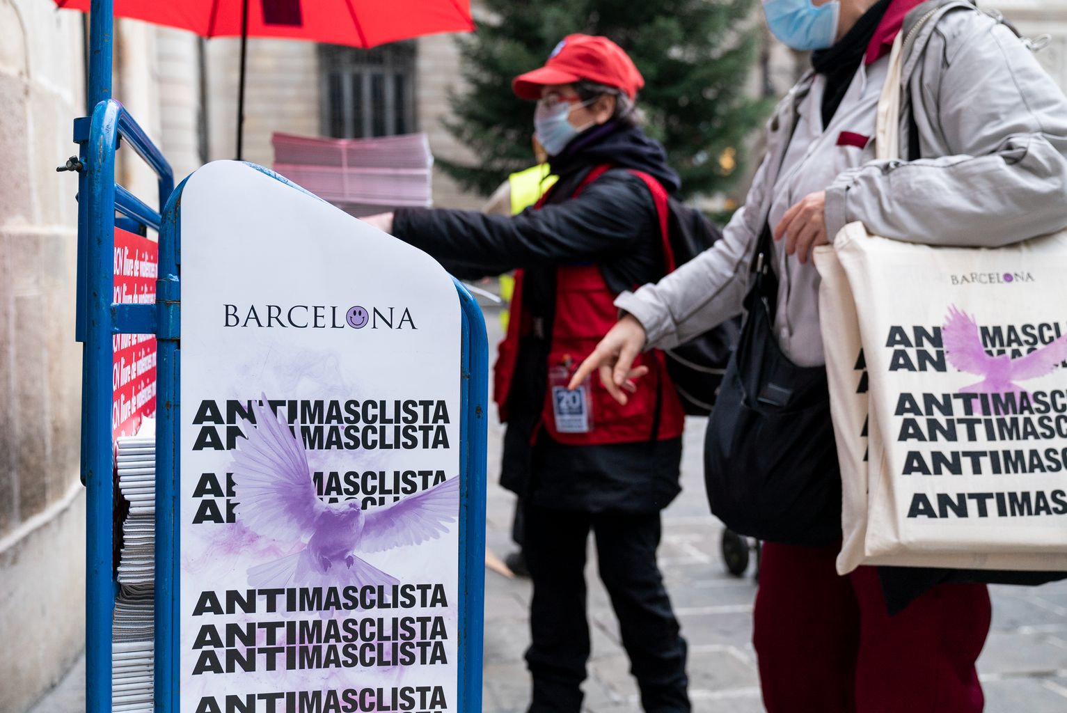 Una repartidora lliura bosses de la campanya del 25-N, Dia Internacional per a l'Eliminació de la Violència vers les Dones, a la plaça de Sant Jaume