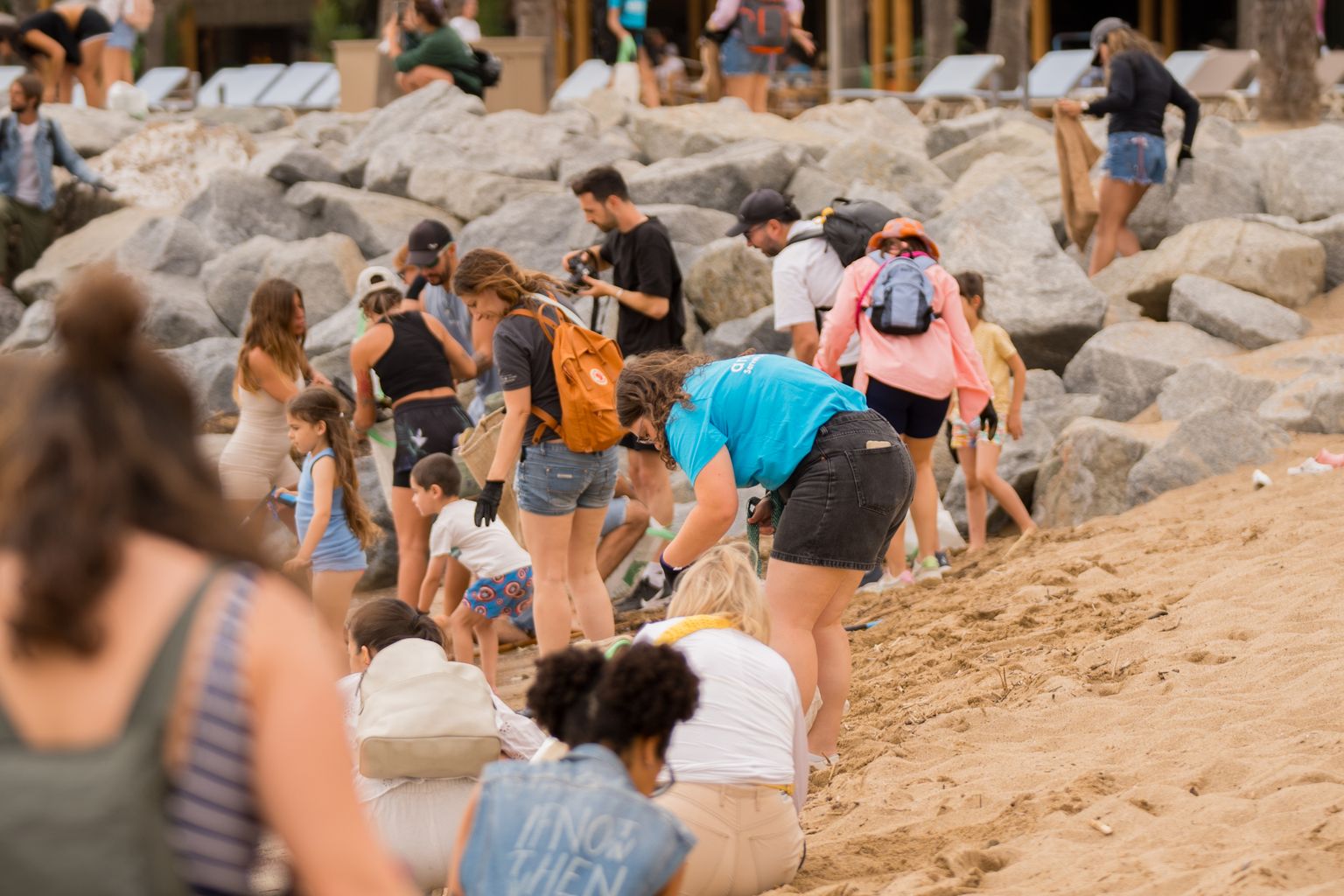 Voluntarios recogiendo residuos en la arena y en las piedras de la playa de la Barceloneta con motivo del Día Mundial de los Mares y el Océano.