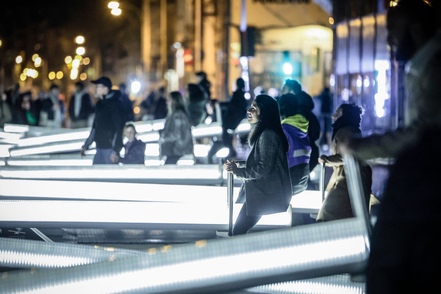 Diversos vianants gronxant-se a la instal·lació artística 'Impulse', de CS Design, al Festival Llum BCN 2025.