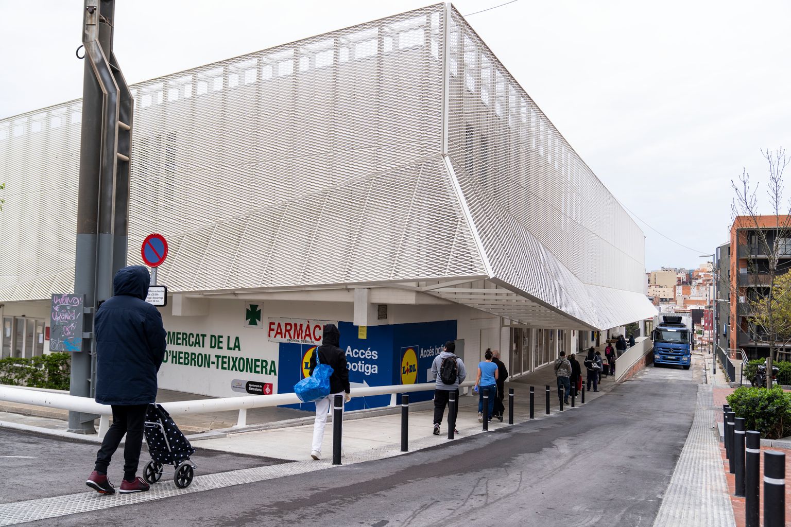 Cua de gent als voltants del Mercat de la Vall d’Hebron on hi ha també un hipermercat esperant per entrar. Molts d’ells porten mascaretes i guarden la distància de seguretat