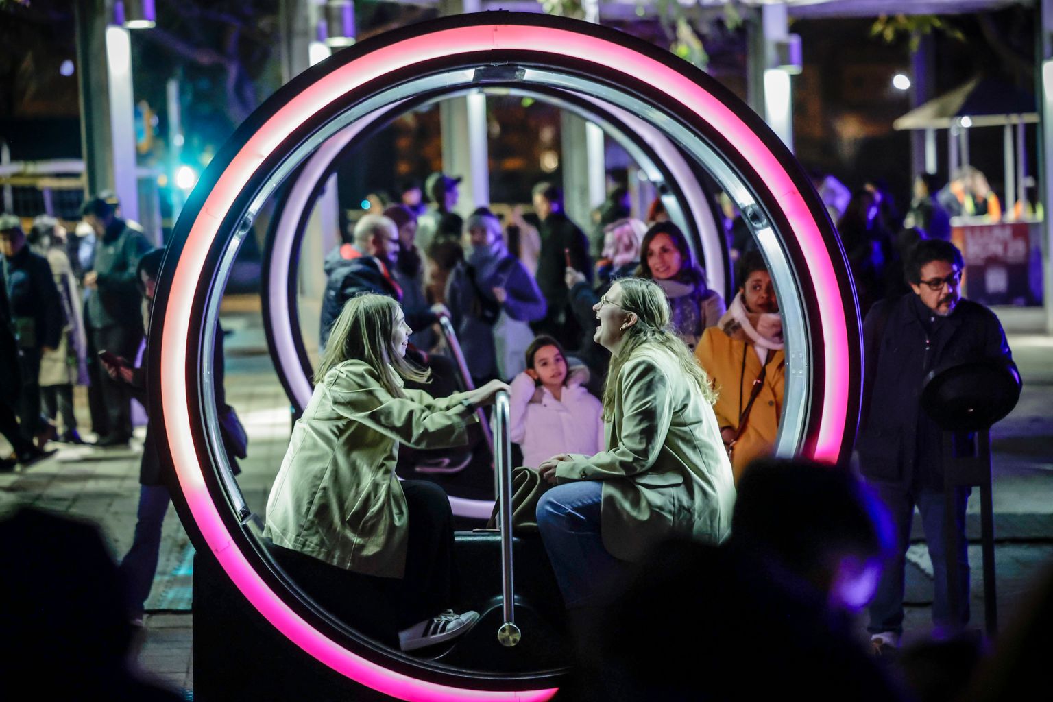 Una parella de vianants gaudint de la instal·lació artística 'Loop', d'Olivier Girouard, Jonathan Villeneuve i Ottoblix, al Festival Llum BCN 2025.