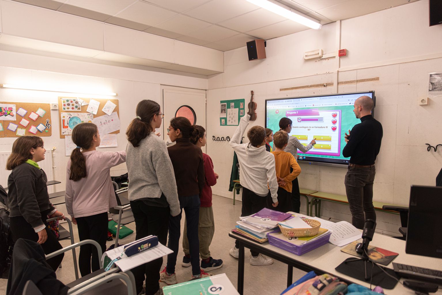 Uns alumnes de llenguatge musical de l'EMM Sant Andreu responen les preguntes d'un Capcut projectades a la pantalla de l'aula