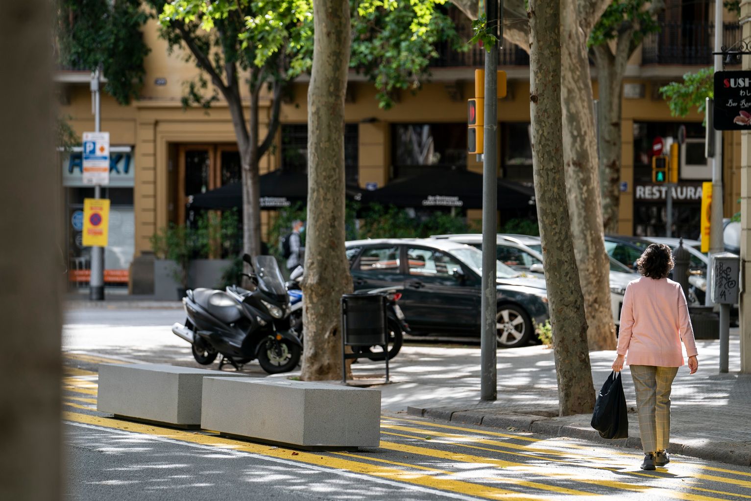 Bancs del carrer del Consell de Cent col·locats a les ampliacions d'espais per vianants. Una dona creua el carrer pel pas de vianants