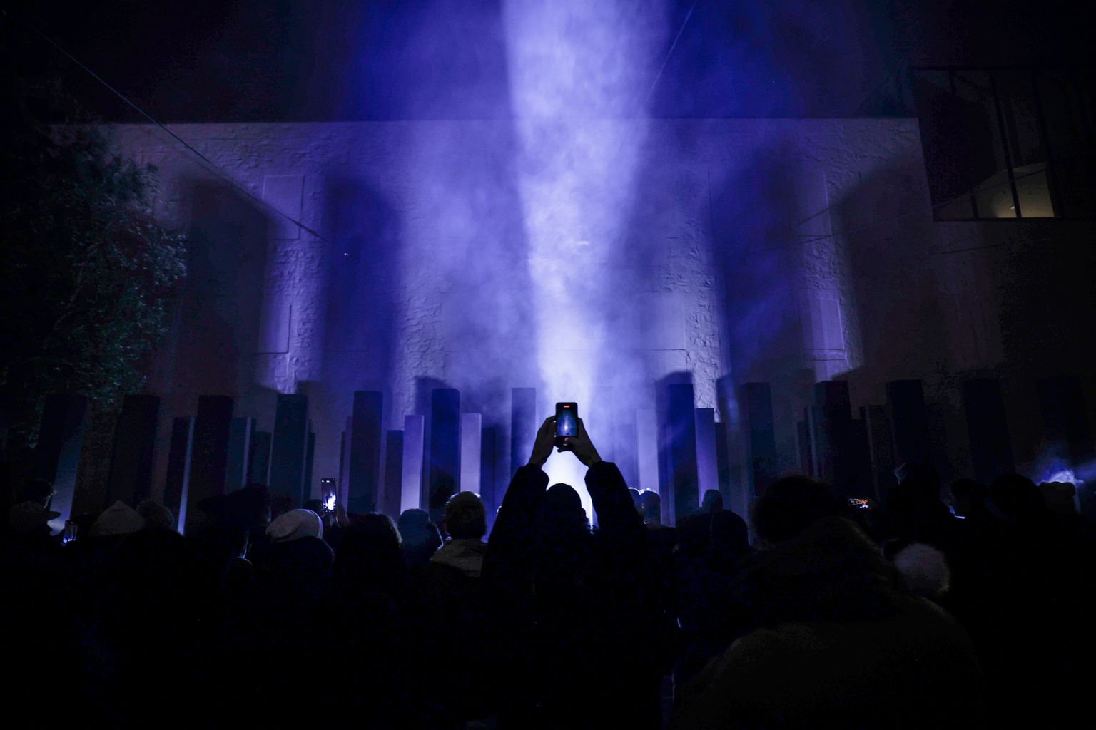 Silueta de unas manos grabando con el móvil en la instalación artística '48 Pillars', de Bruno Ribeiro, en el Festival Llum BCN 2025.