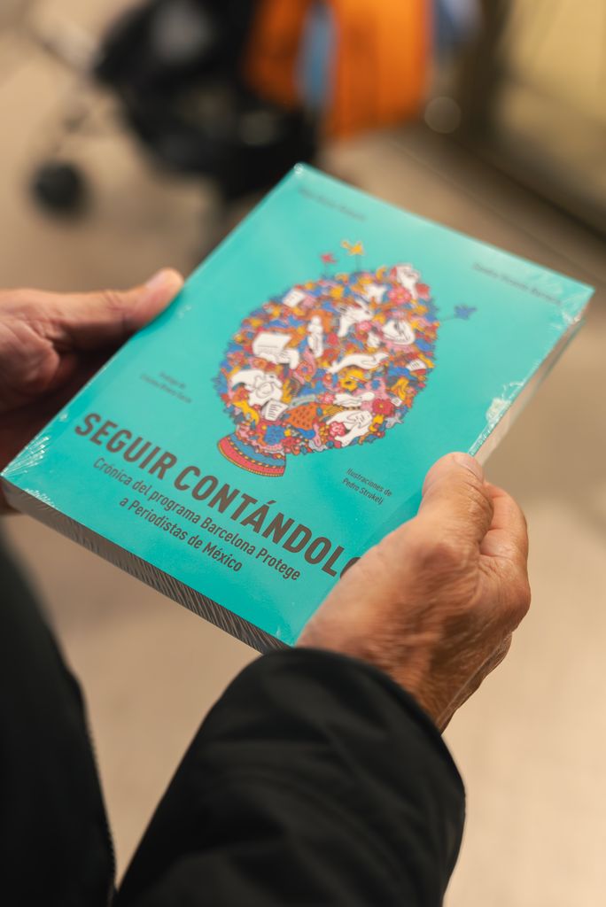 Una persona agafa el llibre “Seguir contándolo. Crónica del programa Barcelona Protege a Periodistas de México” el dia de la presentació