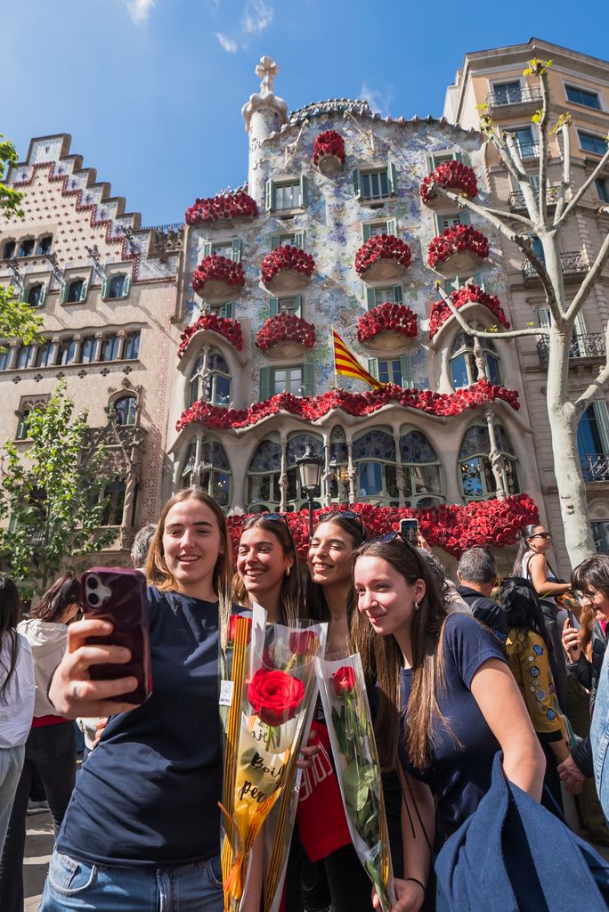 Quatre noies joves es fan un selfie amb roses a les mans davant de la Casa Batlló el dia de Sant Jordi