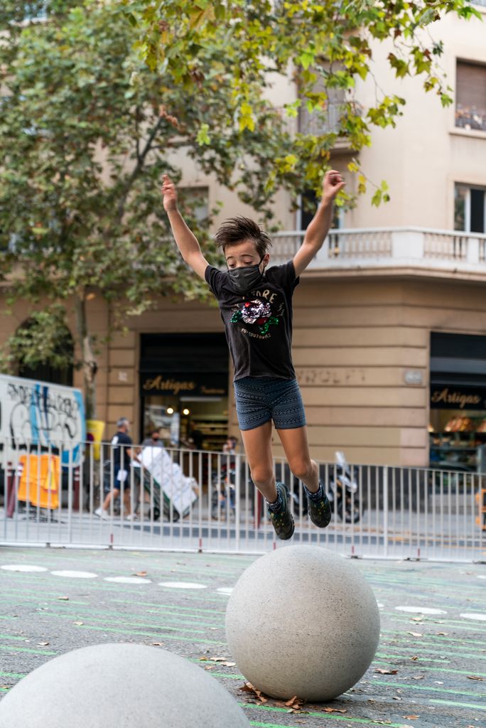 Niño saltando por las esferas colocadas en la zona pacificada de la Escuela Pública Sagrada Família