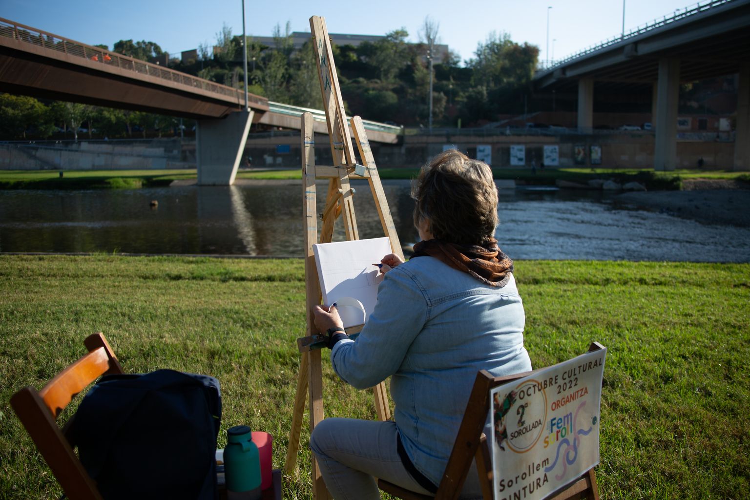 Escorç duna dona pintant un quadre a la riba del riu Besòs.