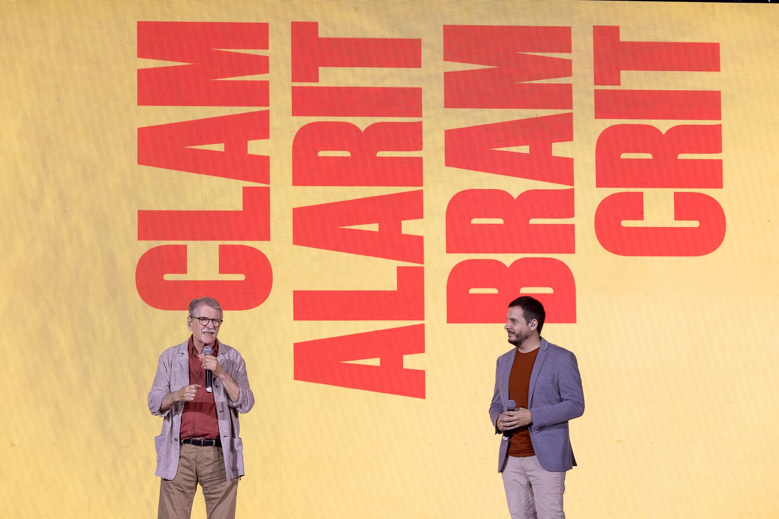 Vicent Torrent i Pau Alabajos a l’escenari de l’acte institucional de la Diada. Al darrere, a la pantalla, hi llegim: “Clam, alarit, bram, crit”.