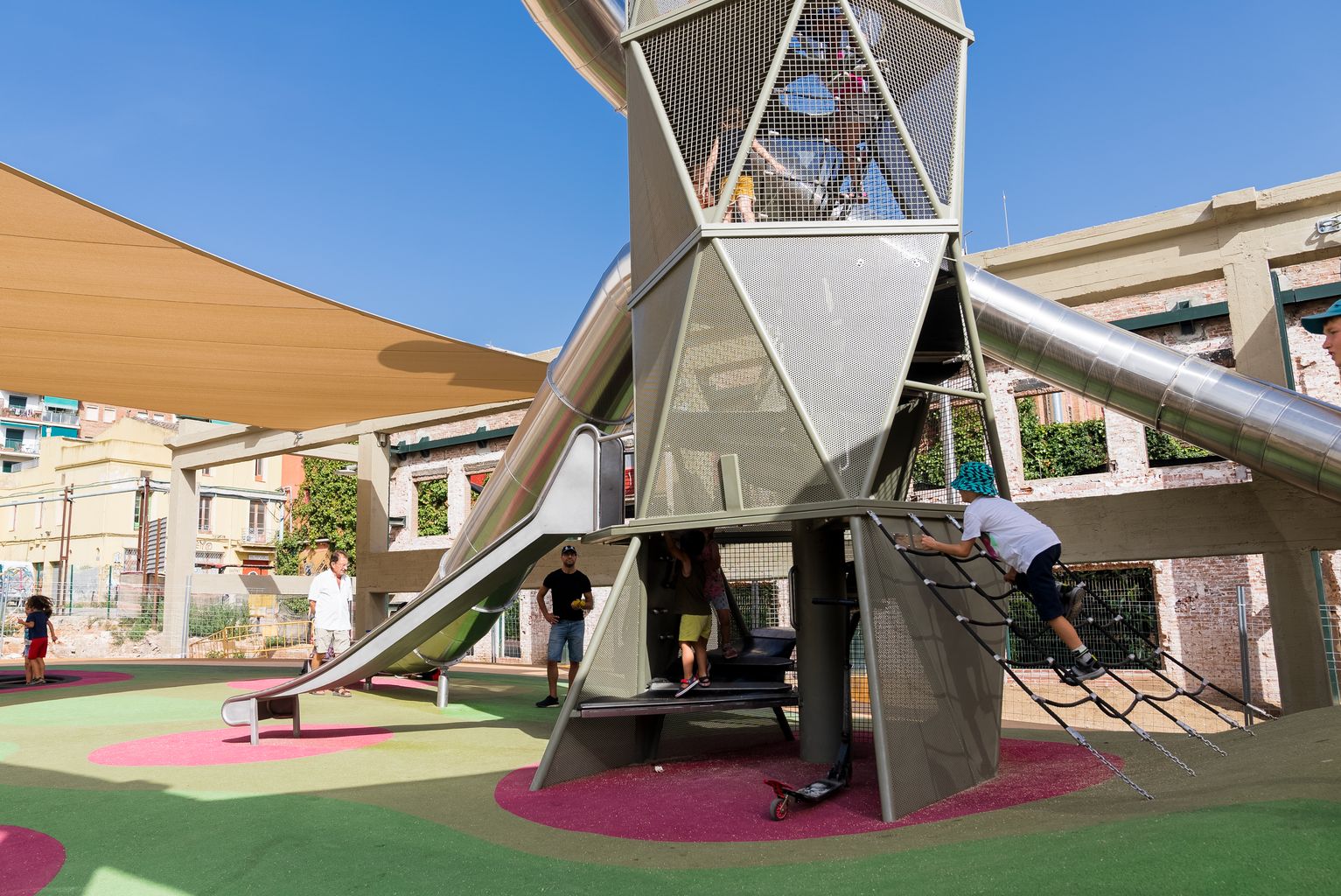 Infants jugant a l'estructura d'escales i tobogans a l'àrea de joc infantil de Can Batlló.