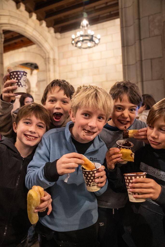 Un grupo de niños comiendo chocolate con bizcochos durante el acto de celebración del Día Escolar de la No Violencia y la Paz