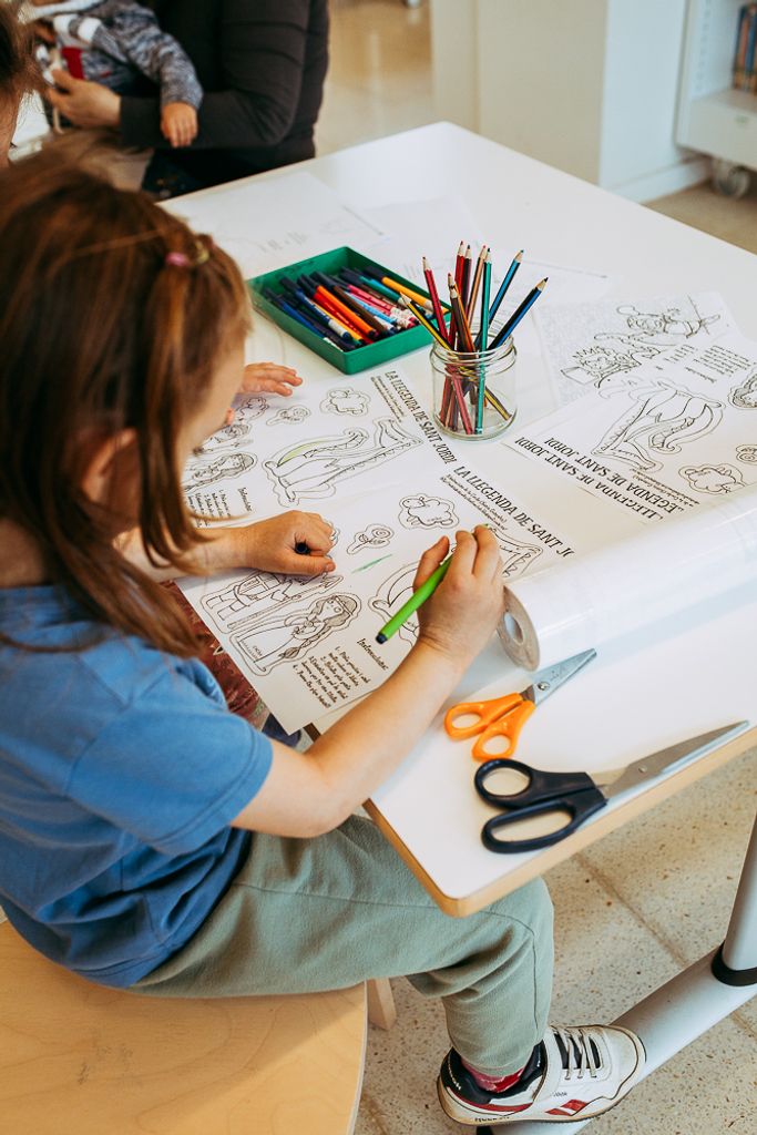 Una nena petita acoloreix uns dibuixos durant la inauguració de l’espai Tres Ulls de la Trinitat Nova.