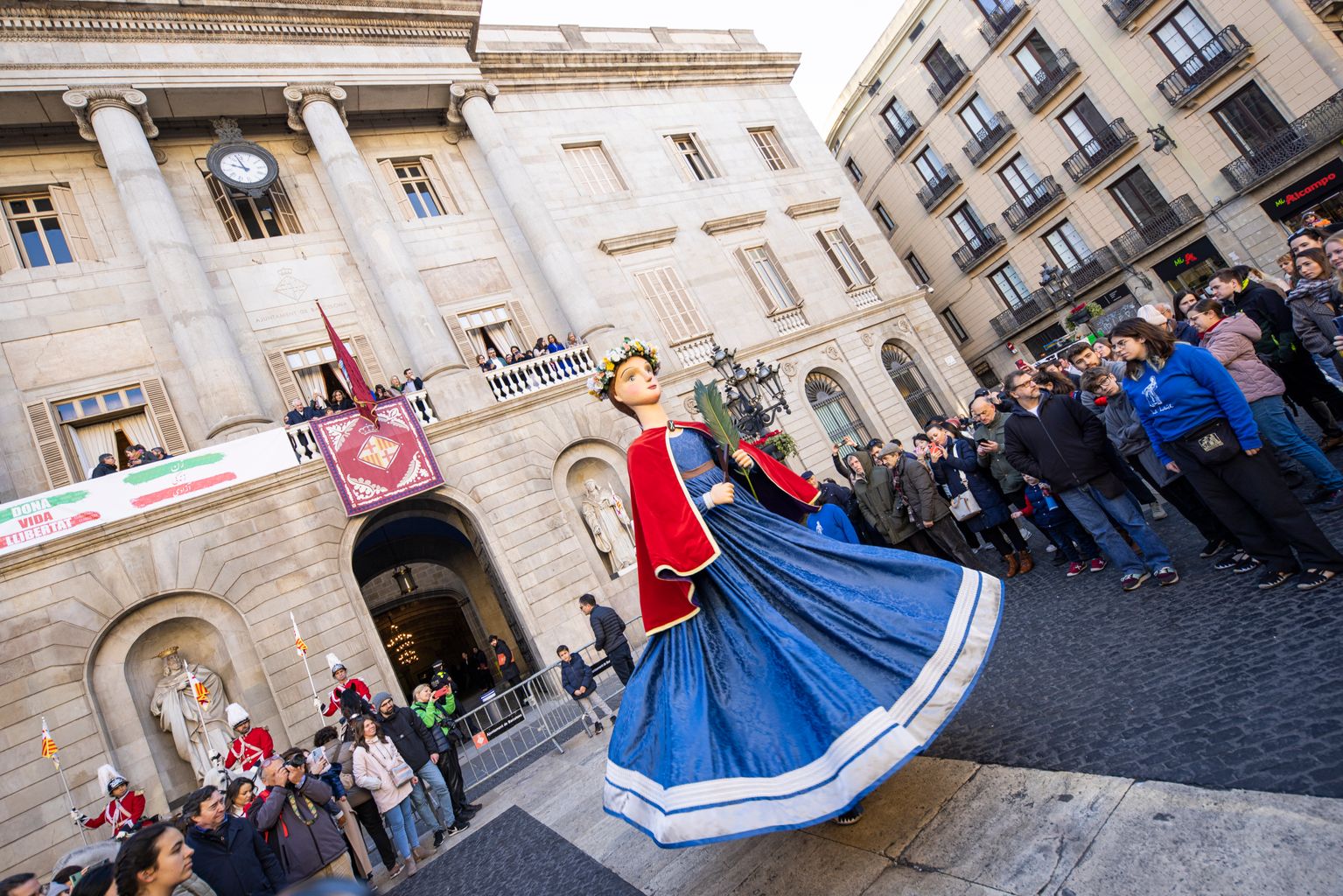 Ball de la Gegantona Laia a la plaça de Sant Jaume durant l'acte de penjada del penó de Santa Eulàlia al balcó de l'Ajuntament
