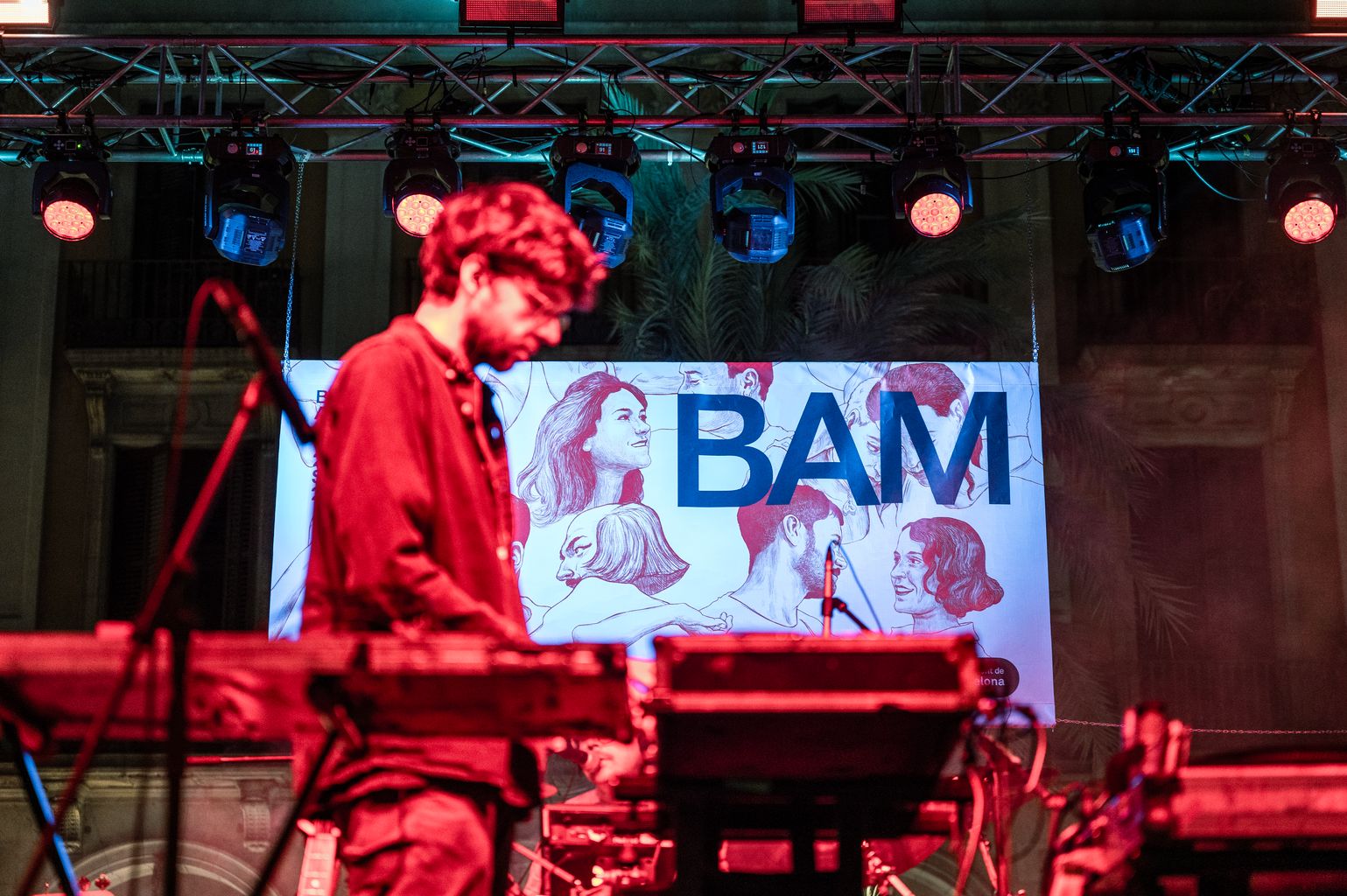 Músic de The Notwist a la plaça Reial, amb el cartell del BAM darrere