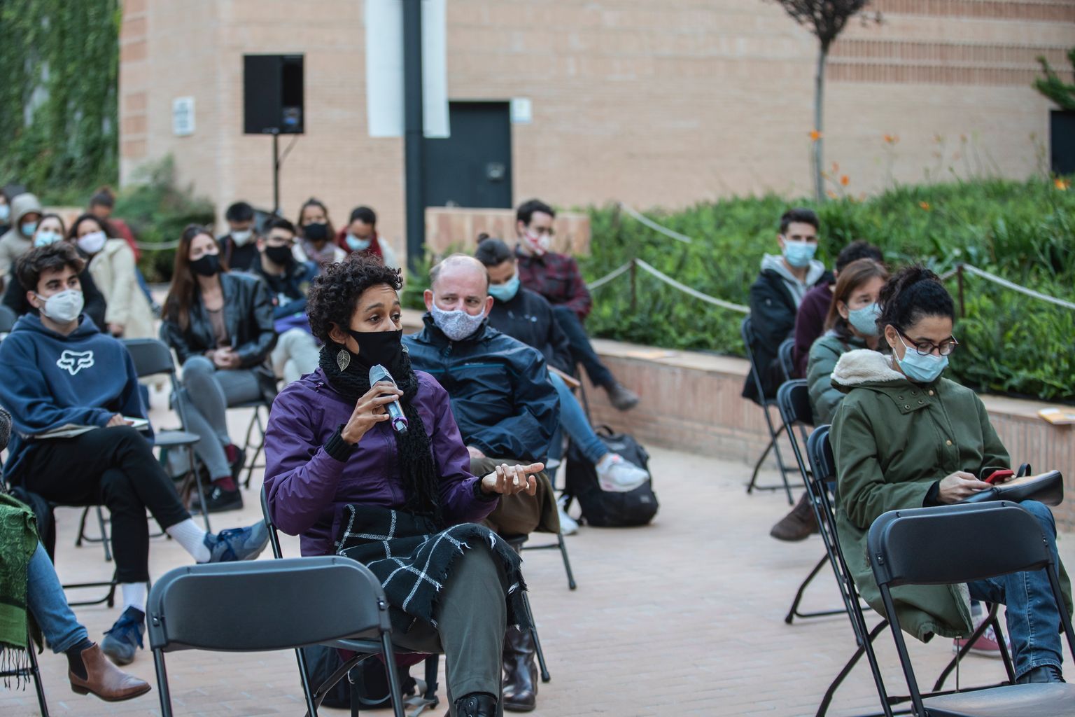 Taula rodona "Som el 99%? De la mobilització social a la política institucional" als jardins d'Agustí Centelles. Una dona del públic fa una pregunta als ponents