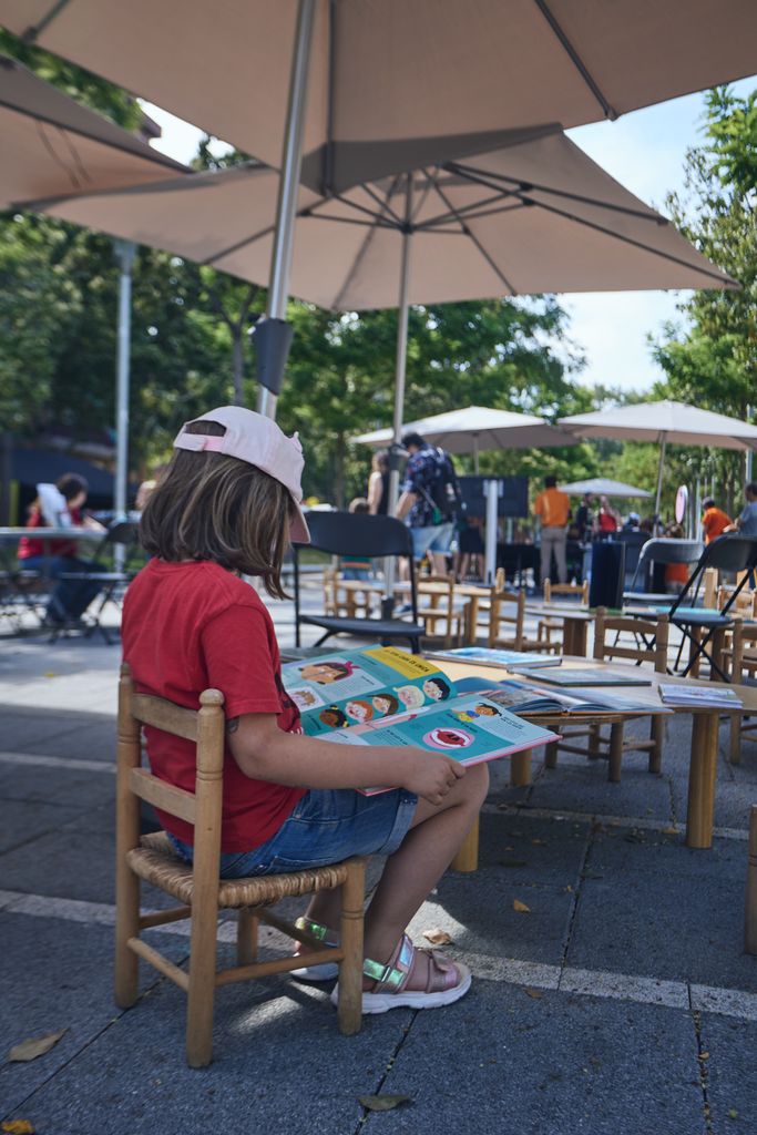 Un infant llegeix un llibre de ciència a l'Espai de lectura de la 16a Festa de la Ciència a la Rambla de Prim.