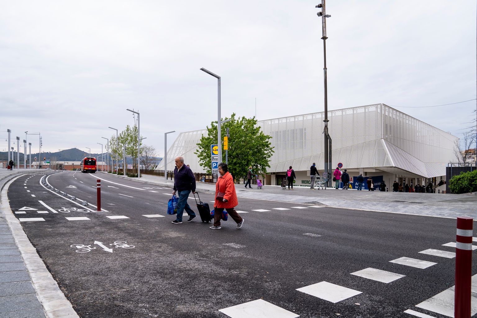 Gent gran carregada de compres travessant el passeig de la Vall d’Hebron allunyant-se del Mercat de la Vall d’Hebron
