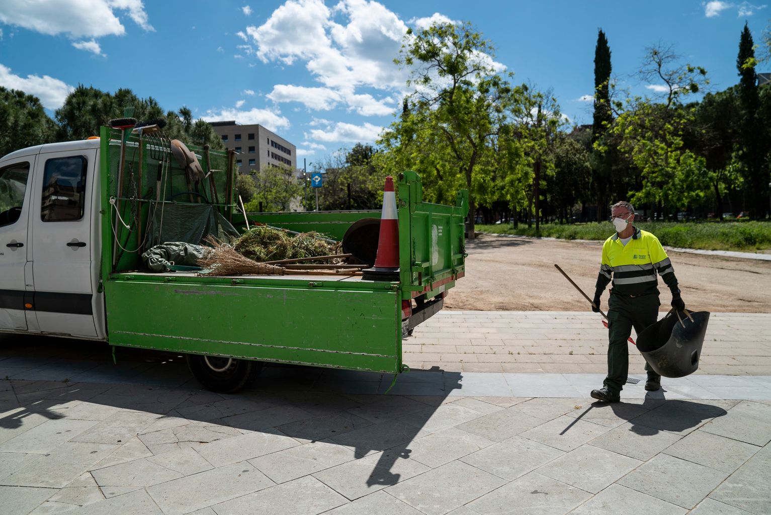 Un dels jardiners amb mascareta, rasclet i cistell al costat del camió de servei