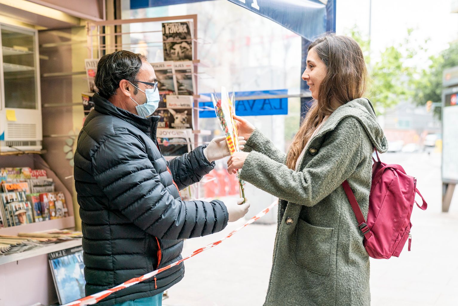 Una dona rep una rosa de mans del quiosquer de les distribuïdes per l’Ajuntament als quioscos de Diverscoop amb motiu de Sant Jordi