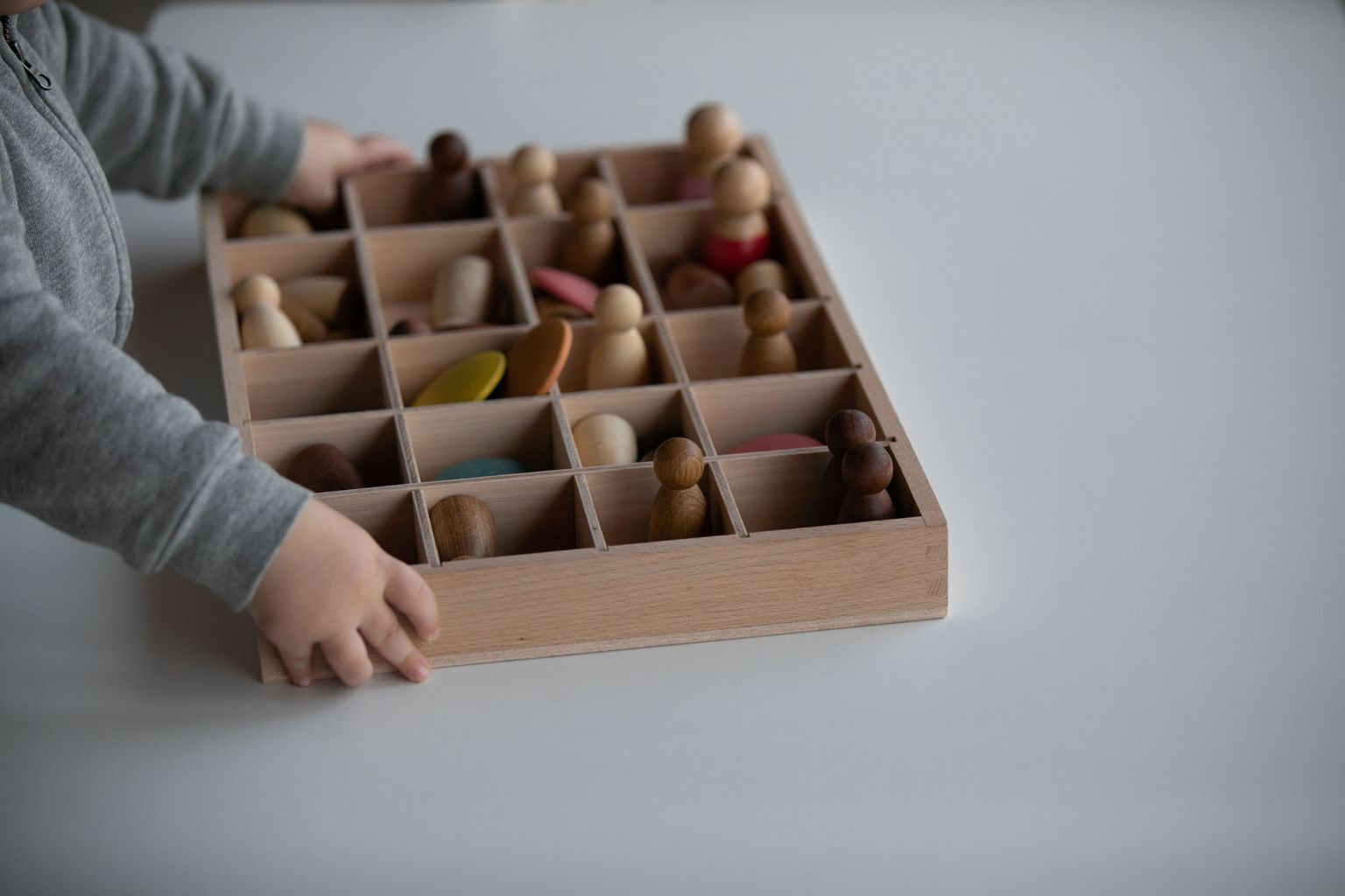 Equipaments, aules i activitat lectiva. Veiem les mans d'un infant jugant amb joguines de fusta.