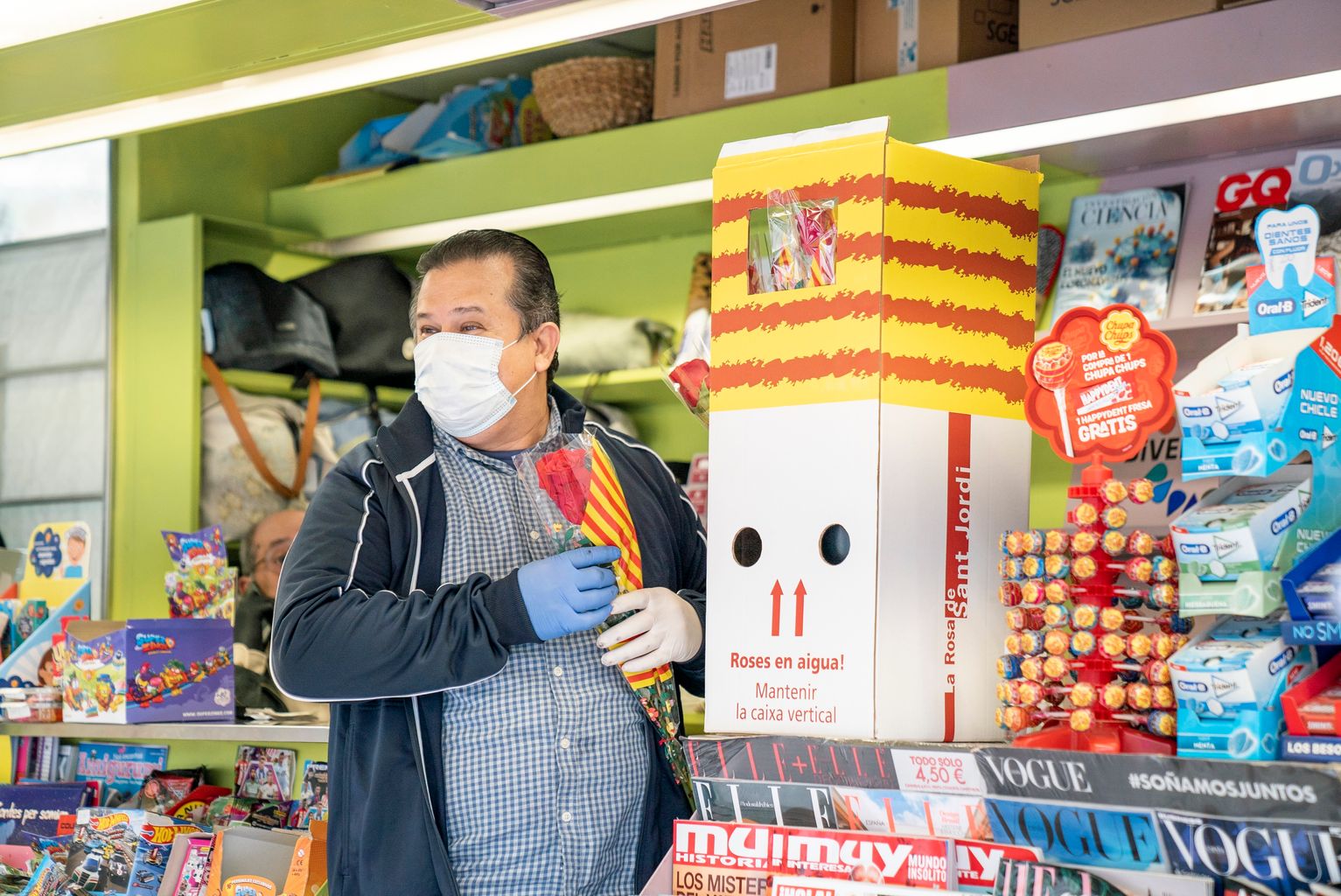 Un dels treballadors dels quioscos de Diverscoop amb mascareta i guants agafa una rosa de les que repartirà per Sant Jordi