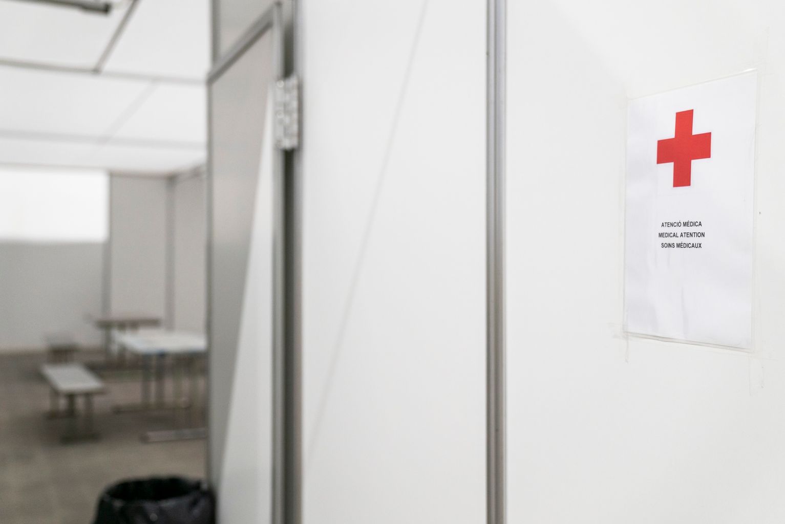 Pavelló per a persones sense llar. Sala per a l’atenció mèdica, tal com indica el rètol de la porta en diferents idiomes i una creu vermella