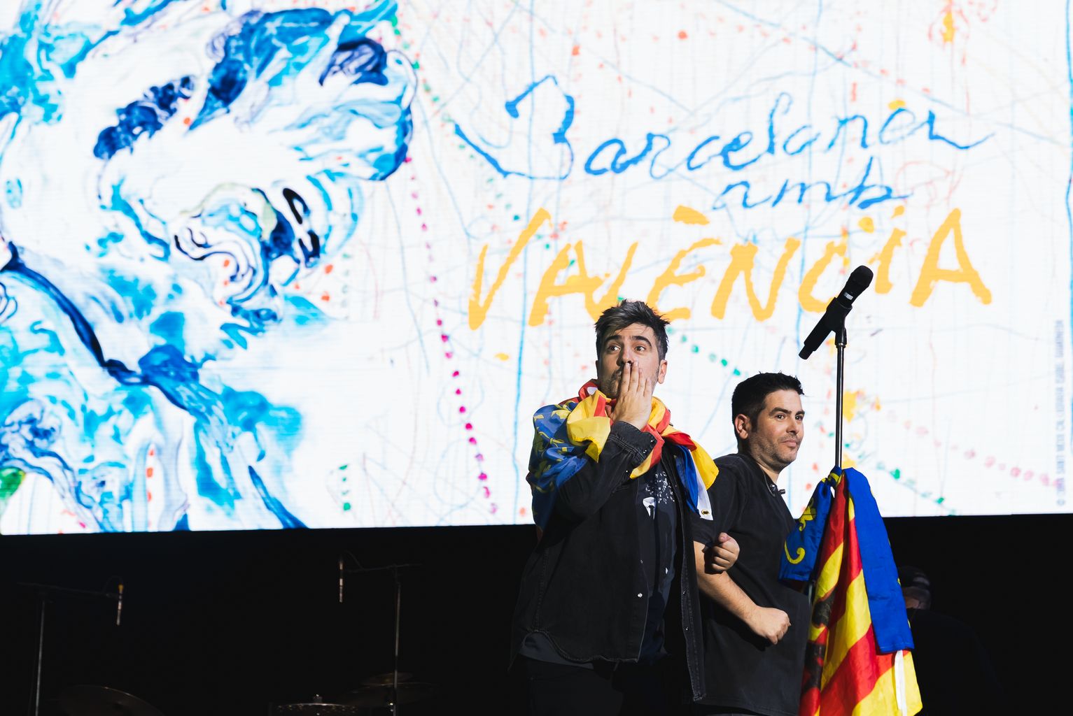 Los hermanos David y José Manuel Muñoz, del grupo Estopa, con banderas valencianas delante del cartel del concierto