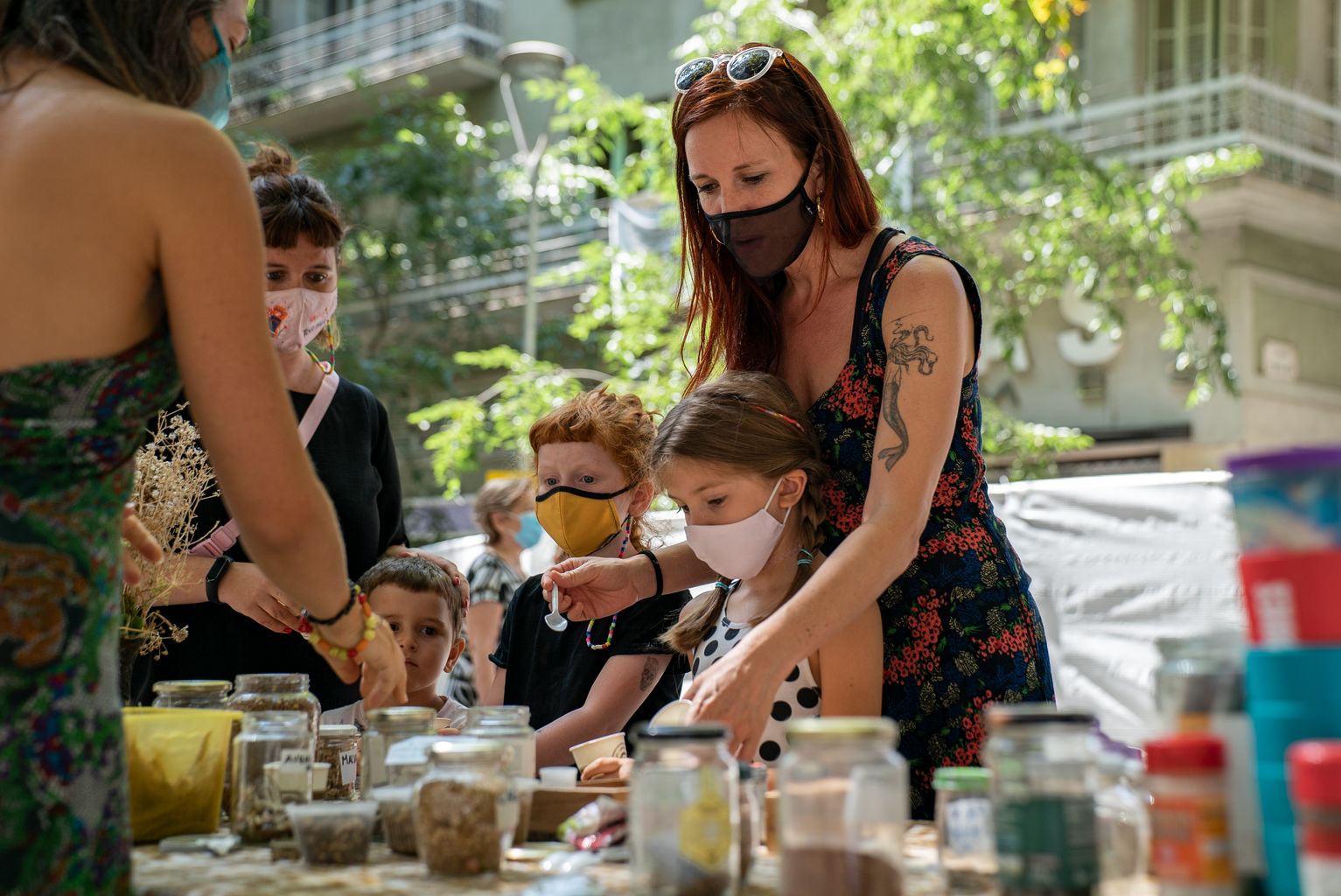 Una mare ajuda els seus fills durant el taller “Fem boletes de llavors: nenodango” de la Festa Major de Gràcia