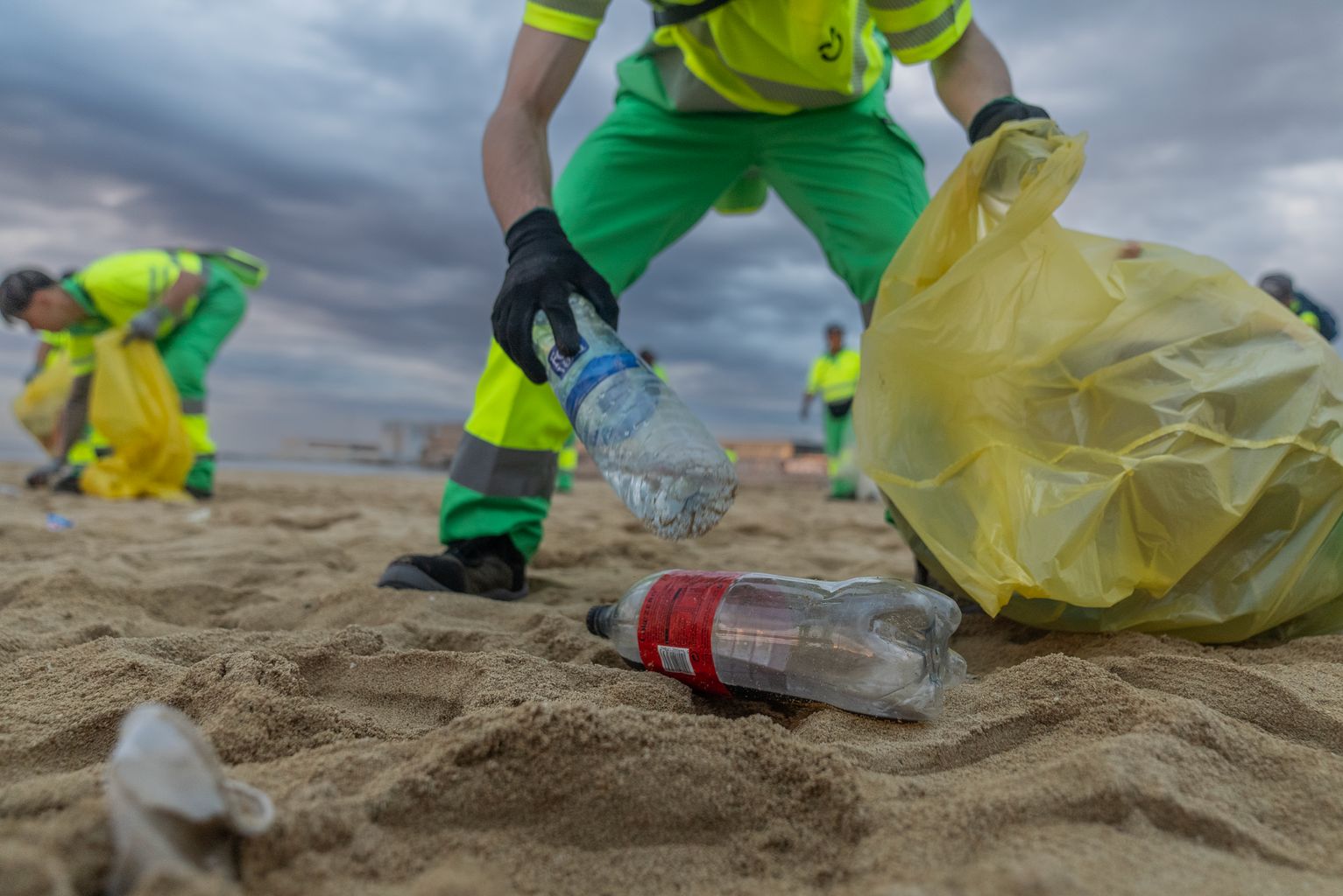 Un trabajador del Servicio de Limpieza recoge envases de plástico de la arena de la playa tras la verbena de San Juan.