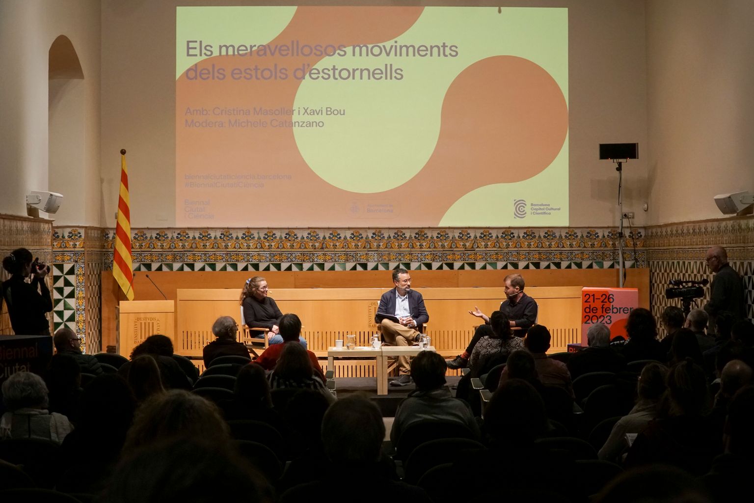 Pla general durant la conversa «Els meravellosos movimients dels estols destornells», a l’Institut d’Estudis Catalans. Damunt de l’escenari: Cristina Masoller, Xavi Bou i Michele Catanzaro.