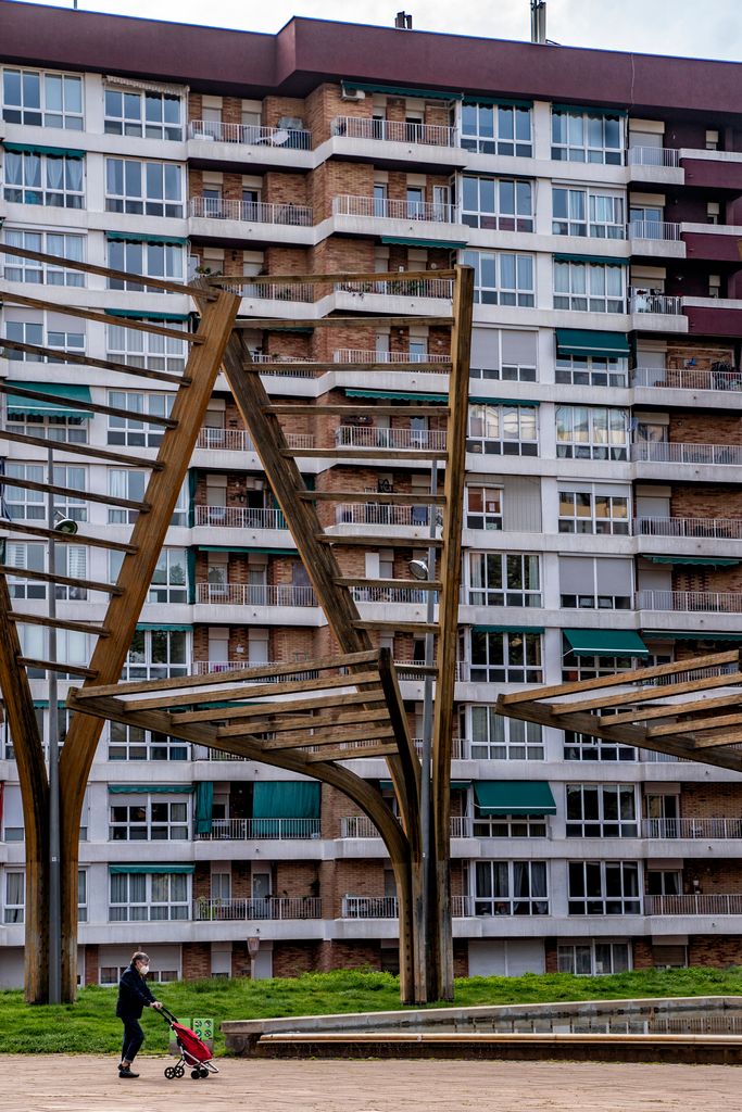 Elements ornamentals de fusta i vidre al parc Central de Nou Barris. Pel seu costat passa una dona amb un carretó de la compra. Districte de Nou Barris. Barri de la Guineueta. 