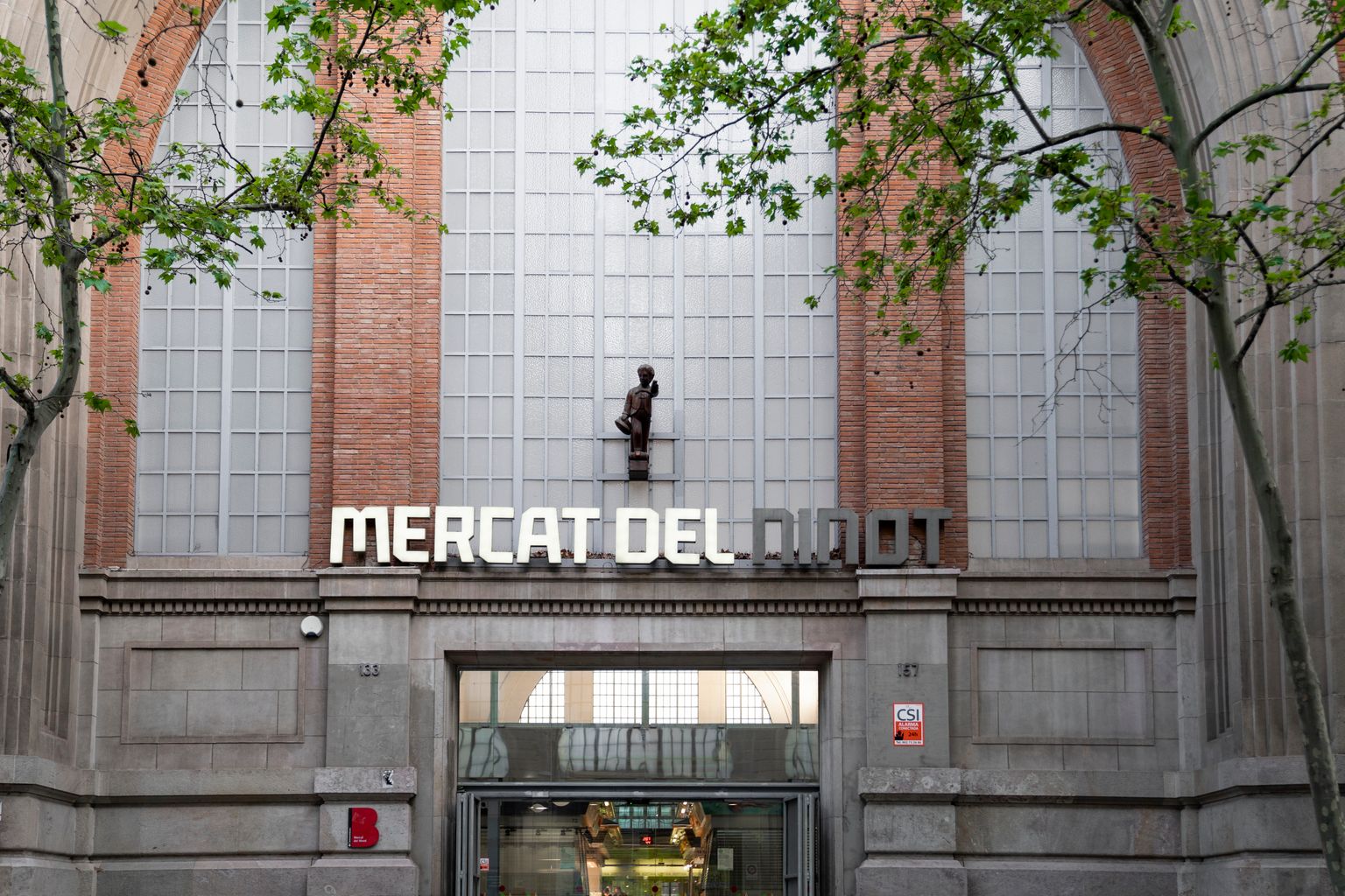 Mercat del Ninot. Façana i entrada principal amb el rètol i la reproducció del “ninot” original que era la figura d’un jove grumet com a mascaró de proa d’un vaixell