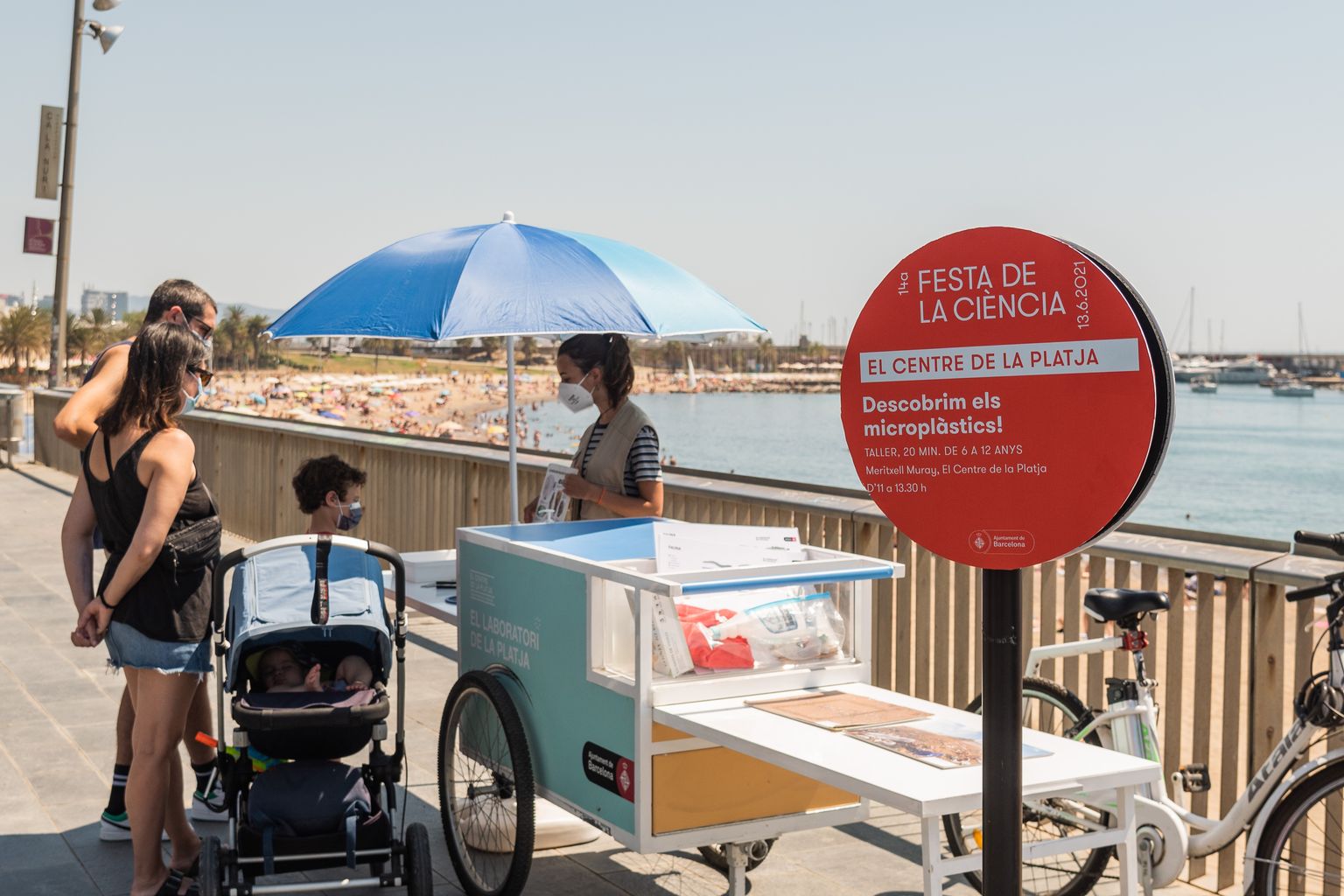 Una família amb infants realitza una activitat al Centre de la Platja, un dels espais de la Festa de la Ciència, consistent en un taller per descobrir els microplàstics