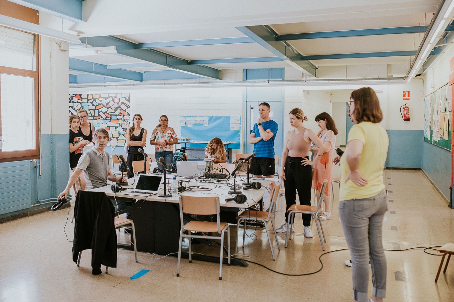 Grup de persones al voltant d’unes taules amb l'equip de so preparant la transmissió de la ràdio comunitària Radioactiva.