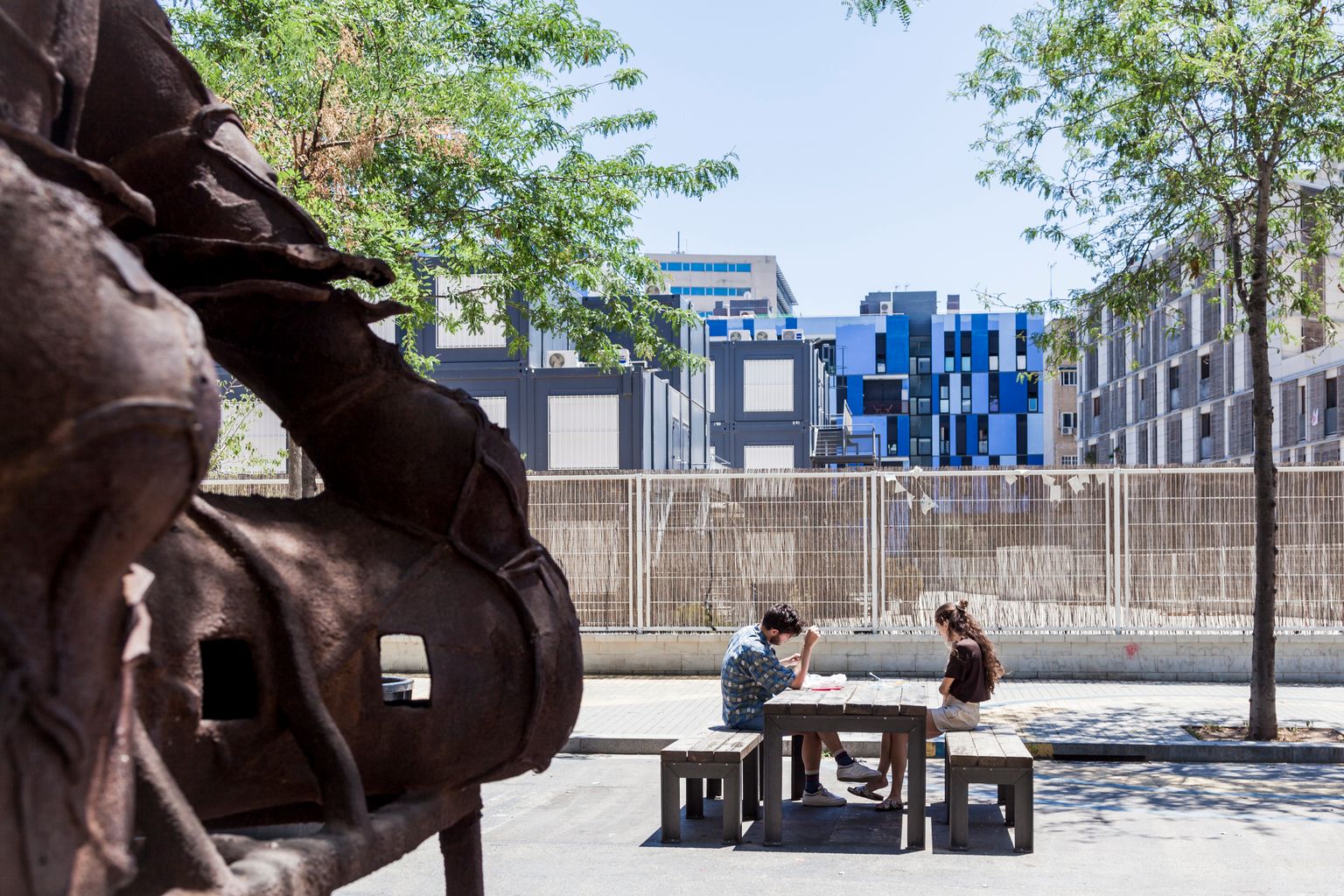 Uns joves gaudeixen de la zona de pícnic al carrer de Sancho de Ávila al costat d’una de les escultures ’Guardians’
