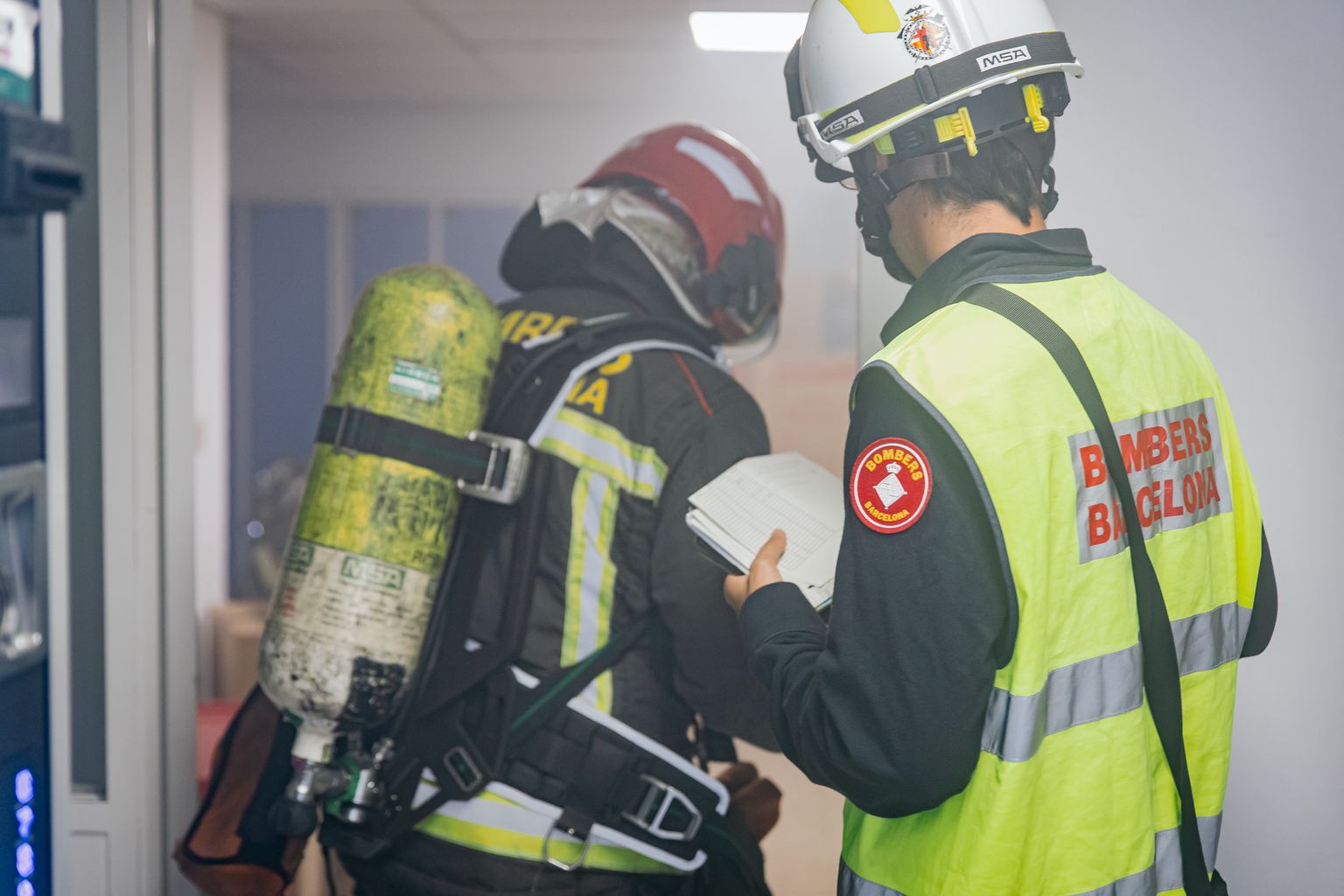 Dos membres del cos dels Bombers de Barcelona a l’interior de l’edifici amb fum de l’Hospital de la Vall d’Hebron durant un simulacre d’incendi.