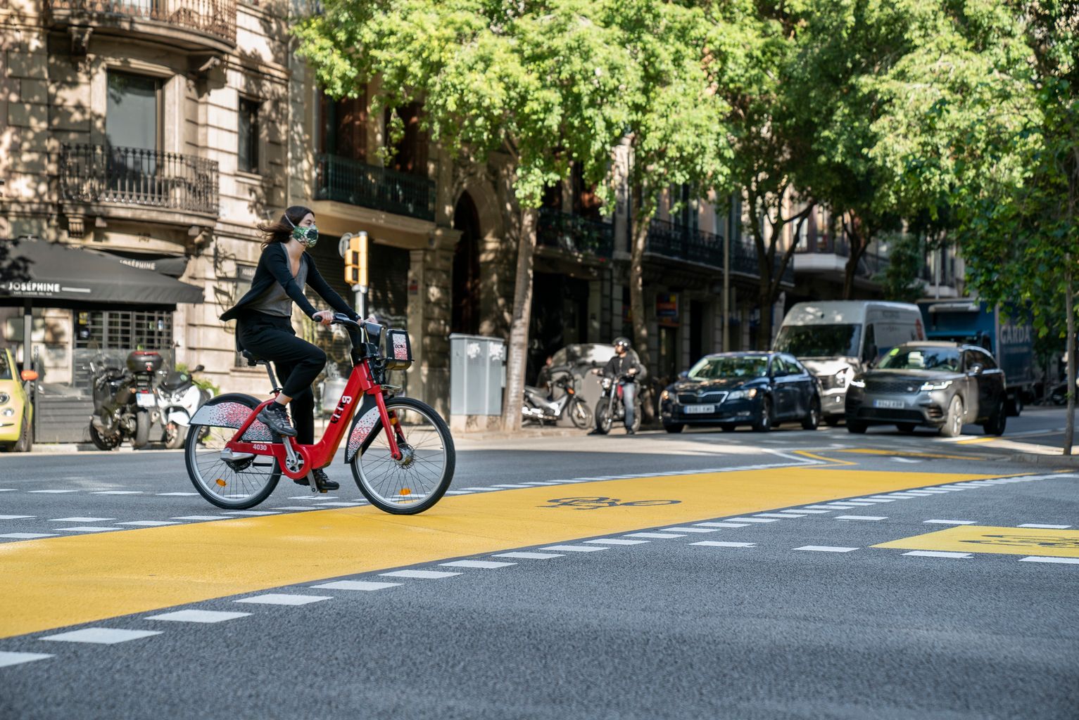 Una ciclista amb mascareta circula amb el Bicing per l'ampliació de l'espai per a bicicletes al carrer de Pau Claris