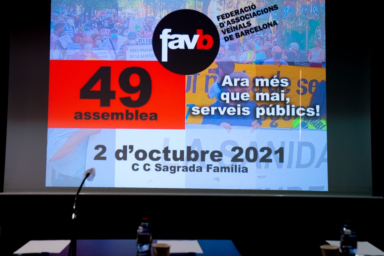 Monitor d'una sala amb la projecció del cartell de la 49a Assemblea de la Federació d'Associacions Veïnals de Barcelona