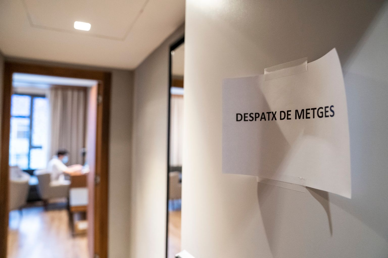 Habitació del Catalonia Plaza destinat a despatx de metges, segons indica un full penjat com a rètol a la porta. Al fons es veu un metge assegut