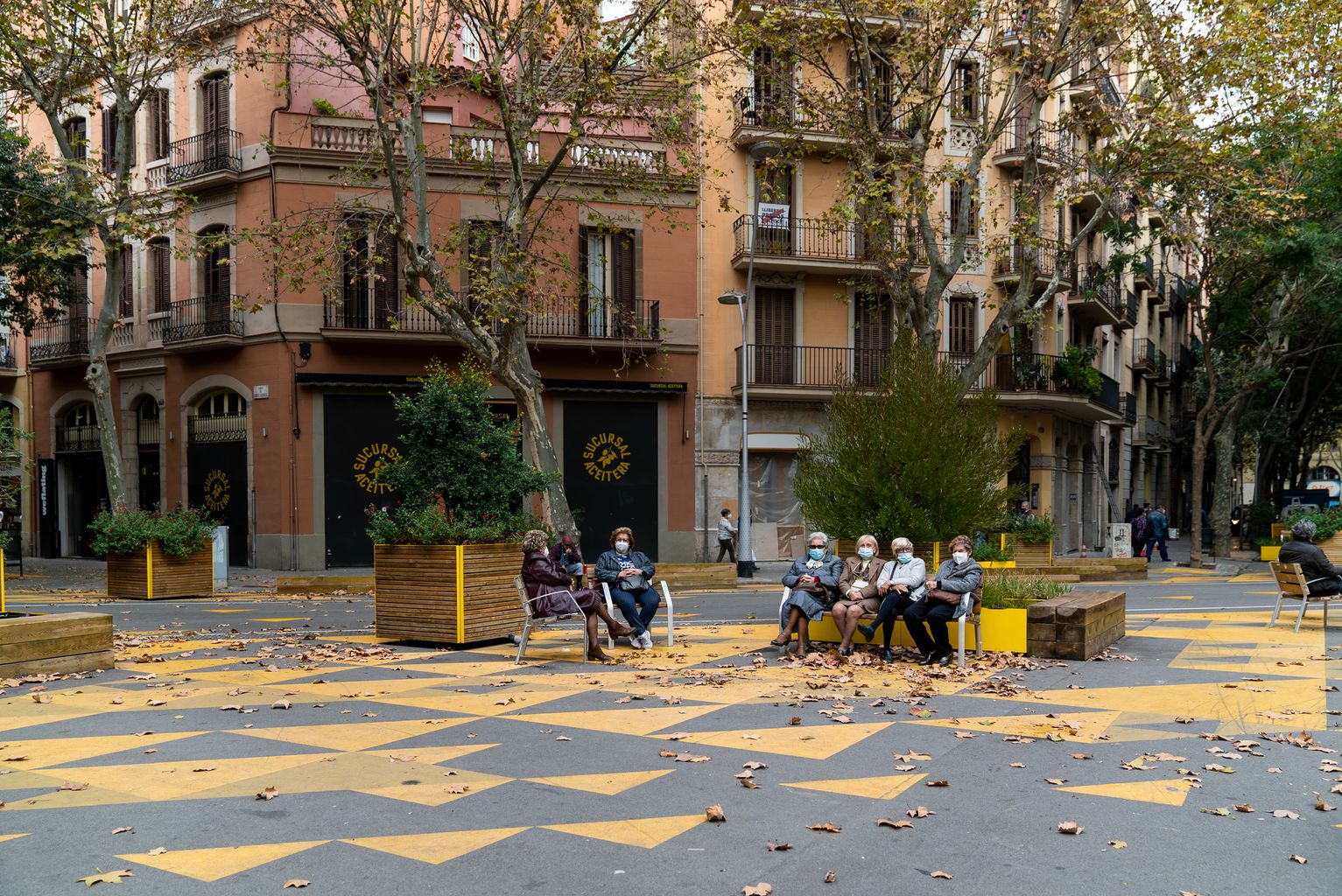 Un grup de dones grans seuen juntes en un banc i aprofiten per xerrar amb les amigues a la superilla de Sant Antoni